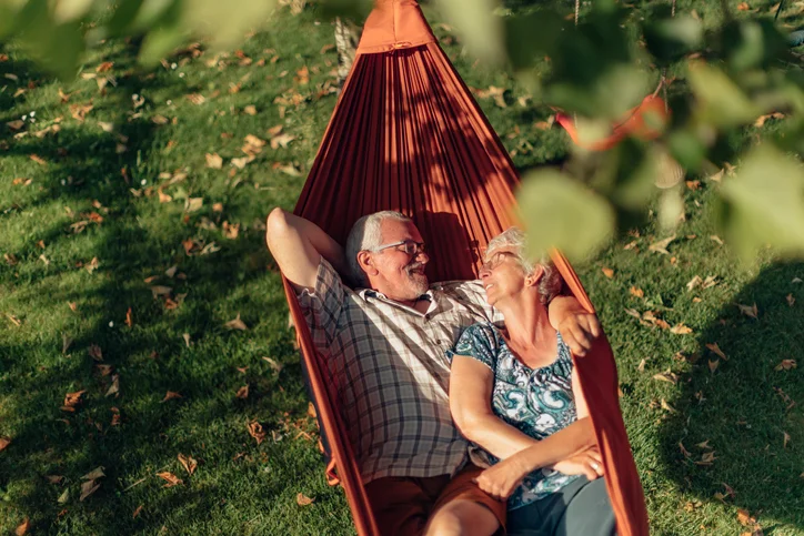 Senior couple embracing in a hammock outside.