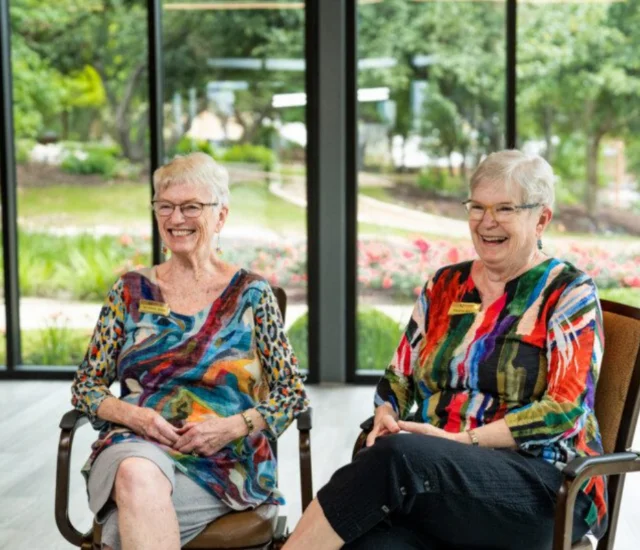 2 senior women sitting in chairs smiling