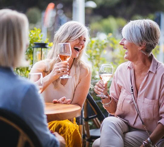 Mature women enjoying a glass of wine, having fun and laughing together at city restaurant