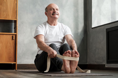 senior man stretches on a yoga mat