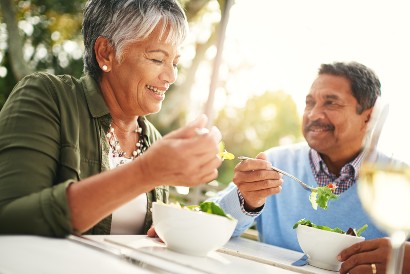 senior couple eating salads together outside at a table