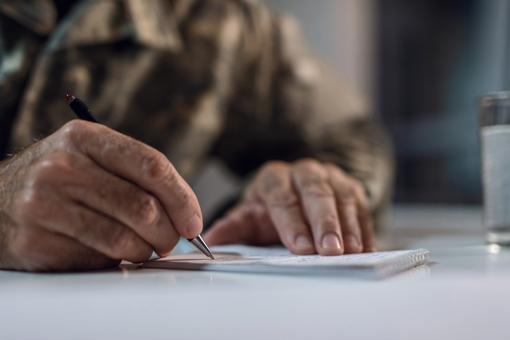 a closeup of a pair of older hands writing a letter