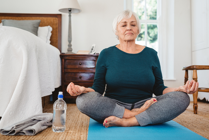 a senior woman practicing yoga alone in her senior apartment