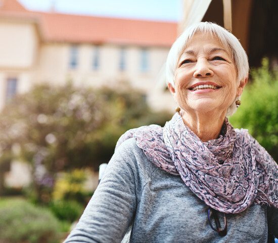 stylish senior woman with silver pixie cut hairstyle smiles off into the distance