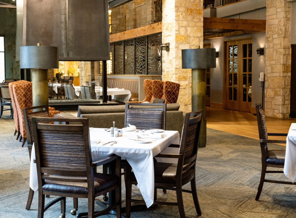 spacious, rustic-chic dining room area with stone accents at Querencia Senior Living Community in Austin, TX