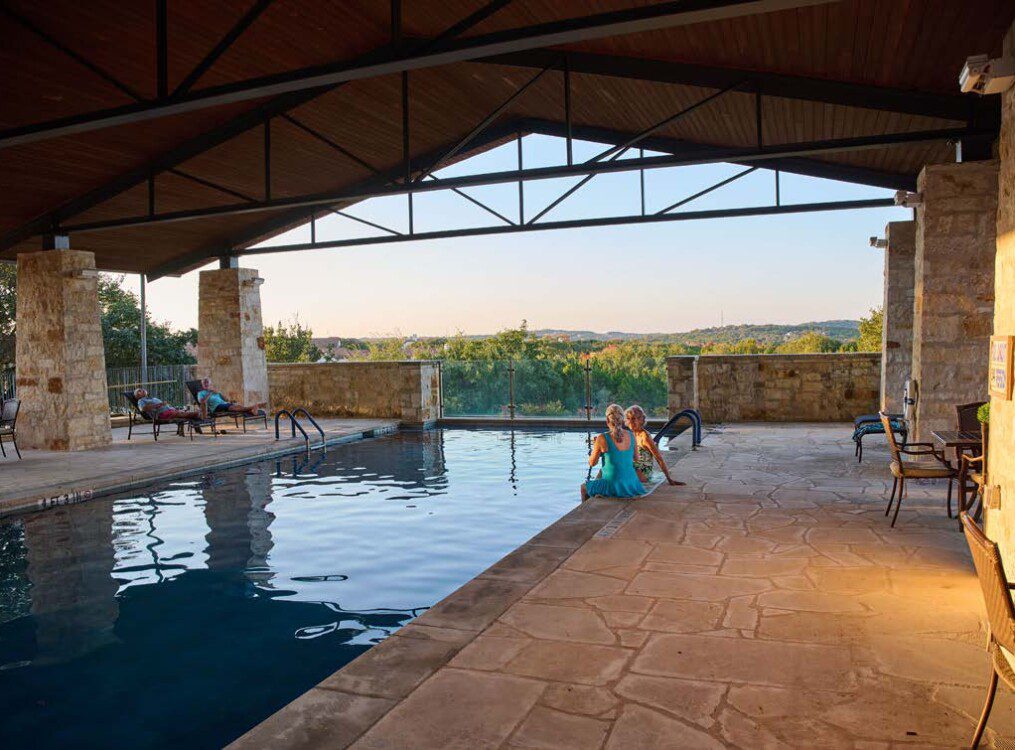 senior women lounge at the gorgeous outdoor pool at Querencia Senior Living Community enjoying drinks