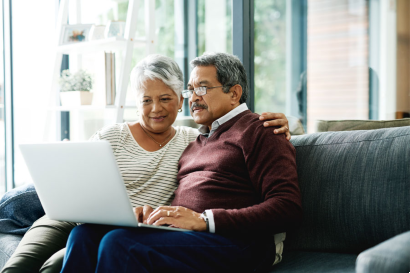 Senior couple looking at a laptop screen together while sitting on the couch