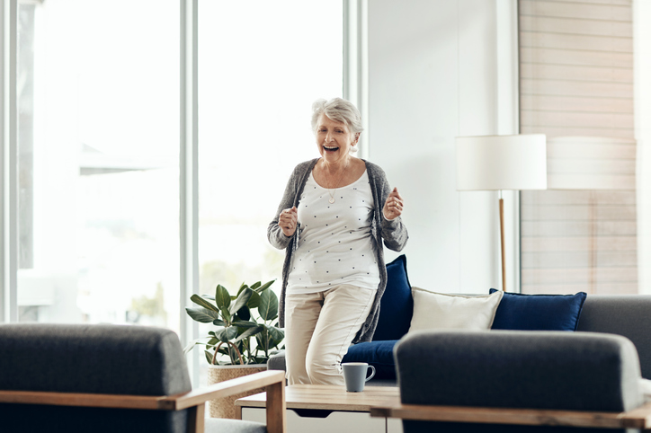 a senior woman dancing and smiling in her independent living apartment