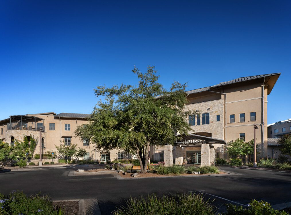 view of the beautifully landscaped exterior entrance of the Health Services building at Querencia Senior Living Community in Austin, TX