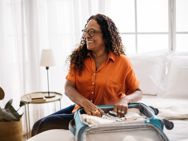 Senior woman smiling as she packs for an upcoming trip.