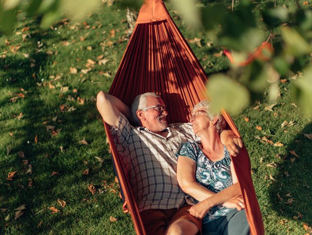 Senior couple embracing in a hammock outside.
