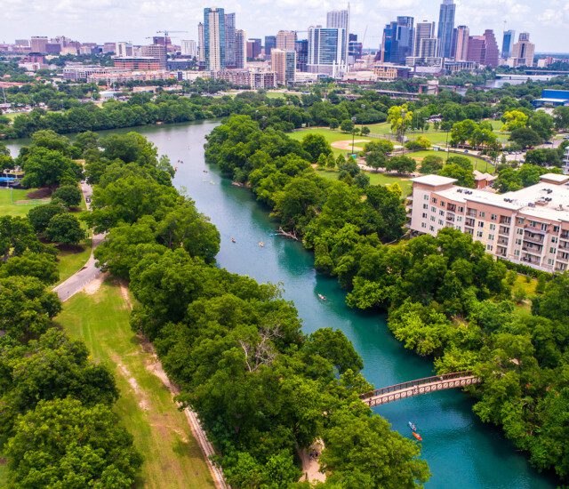aerial view of the Colorado River leading to the dazzling urban skyline of Downtown Austin, TX