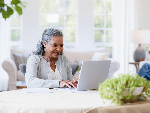 Senior woman smiling as she uses her laptop.