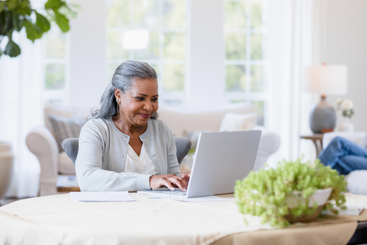 Senior woman smiling as she uses her laptop.